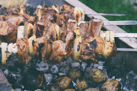 barbecue marinated meat with onion and bacon. Shashlik or Shish kebab preparing on grill over charcoal in nature. Shashlyk skewered meat . BBQ grilling.の写真素材
