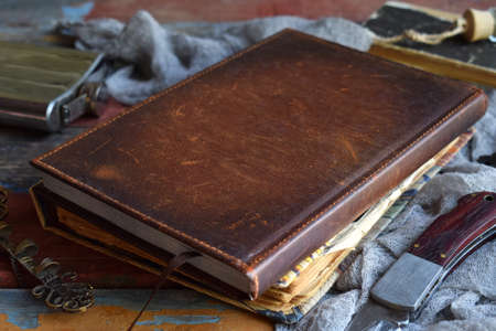 Things hunter for evil, demons, vampires and zombies - an old notebook, a book with spells, a knife, flask of holy water, pen bone, alcohol, a cross. Men's accessories on a dark backgroundの写真素材