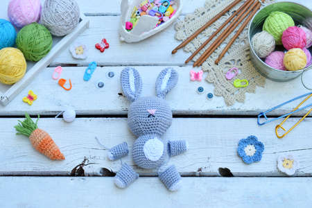 Making rabbit with carrot. Crochet bunny for child. On the table threads, needles, hook, cotton yarn. Step 1 - knit all details of toy. Handmade crafts. DIY concept. Small business. Income from hobbyの写真素材