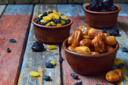 Mix of different varieties of dried fruits on wooden background - dates, apricots, prunes, raisins. Organic healthy food. Excellent snack or dessert.の写真素材