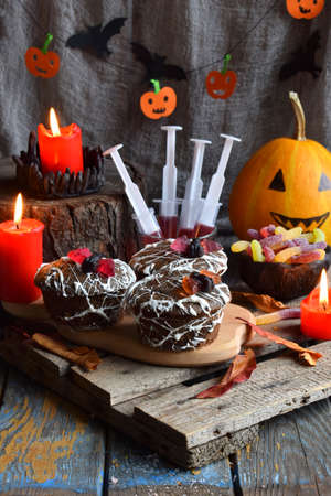 Halloween trick or treat party. Funny delicious sweets and pumpkin on wooden background - muffins, cupcakes, juice, jellies, candy.の写真素材
