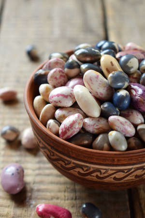 Assortment of young legumes and beans of different varieties and colors in a clay bowl. Raw food....