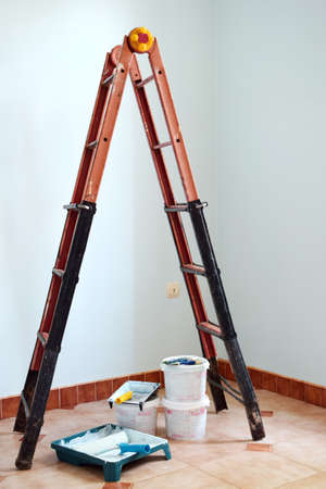 Freshly painted light blue room with painting equipments at home and ladder. Painting accessories...