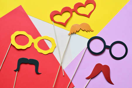 Colorful props for party. Carnival accessories set. Paper glasses, hat, lips, moustaches, tie on wooden sticksの写真素材