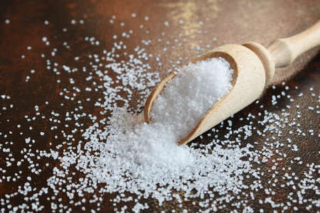 Sea salt, finely ground scattered in wooden spoon on black backgroundの写真素材