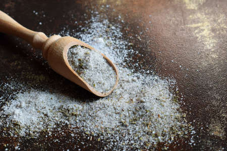 Ayurvedic herbal salt in wooden spoon. Sea salt with aromatic herb - rosemary oregano, sage,...