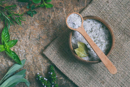Ayurvedic herbal salt in wooden spoon. Sea salt with aromatic herb - rosemary oregano, sage, marjoram, basil, thyme, mint, bay leaf. Copy space.の写真素材