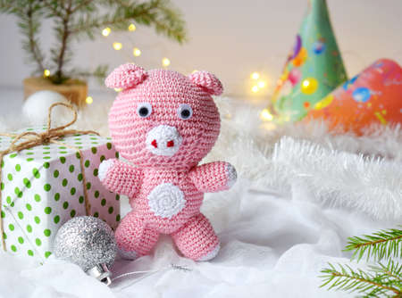Pink pig, symbol of 2019 and gift on white background. Happy New Year and Merry Christmas card. Crochet toy for child. Handmade crafts on holiday with your own hands. DIY concept. Copy space.の写真素材