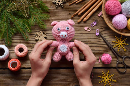 Pink Pig, symbol of 2019, Happy New Year. Crochet toy for child. On table threads, needles, hook, cotton yarn. Handmade crafts on holiday with your own hands. DIY concept.の写真素材