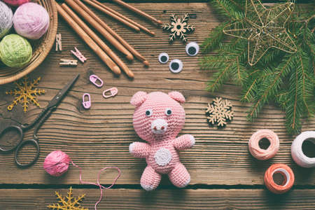 Pink Pig, symbol of 2019, Happy New Year. Crochet toy for child. On table threads, needles, hook, cotton yarn. Handmade crafts on holiday with your own hands. DIY concept.の写真素材