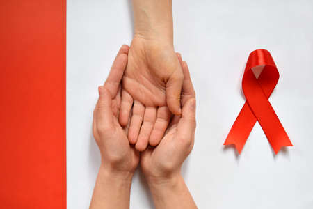 Patient support with diagnosis of HIV AIDS. Womens hands holding hand on white background. World...