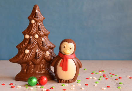 Chocolate Christmas tree and penguin on blue background. Happy New Year and Merry Christmas concept. Copy space.の写真素材