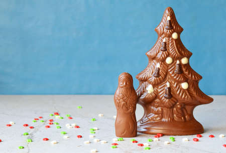 Chocolate Christmas tree and Santa Claus on blue background. Happy New Year and Merry Christmas...
