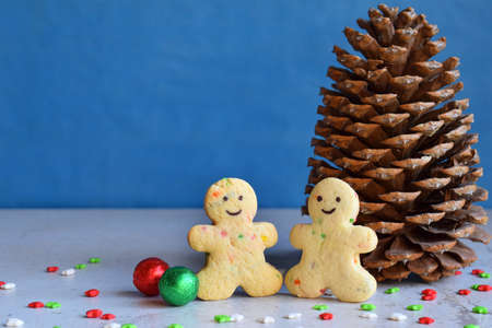Big pine cone, gingerbread men and gifts on blue background. Happy New Year and Merry Christmas concept. Copy space.の写真素材