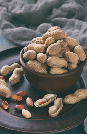 Peanuts in nutshell and peeled peanut on wooden background. Healthy and dietary nutrition. Raw food