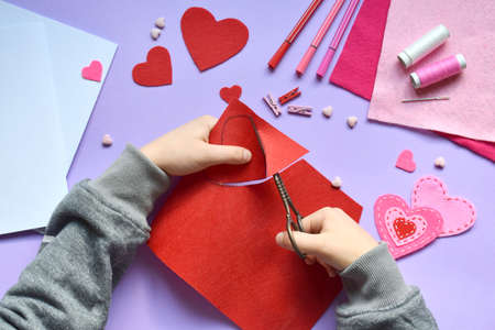 Making of handmade Valentine greeting card from felt. Children's DIY, hobby concept, gift with your own hands. Valentine's Day decoration. Step 2. Cut the heart template.の写真素材
