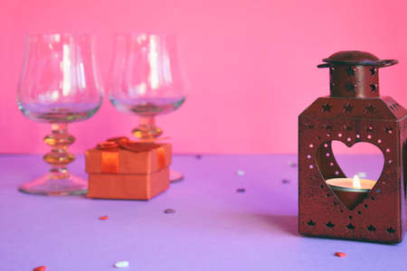 Red candlesticks with heart, present box and wine glasses on pink background. Valentine's Day theme or greeting card conceptの写真素材
