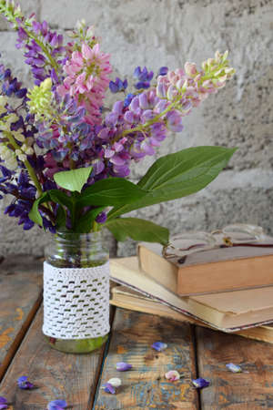 Pink, purple lupine flowers bouquet in vase and old book. Birthday, Mother's day, Valentine's Day, March 8, Wedding card or invitation. Festive Floral decorative background. Copy space.の写真素材