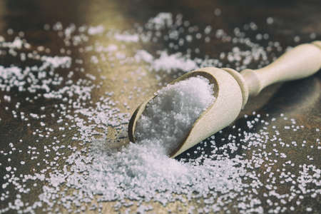 Sea salt, finely ground scattered in wooden spoon on black backgroundの写真素材