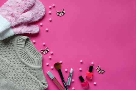 Knitted sweater, warm mittens, nail polishes, lipstick on a pink background. Winter and autumn set...
