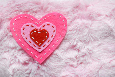Felt hearts on pink fur texture. Valentines Day background or greeting card concept
