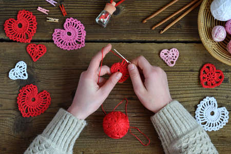 Crochet openwork hearts. Making of handmade decoration. Valentines Day crafts. Childrens DIY, hobby concept, gift with your own hands. Small business. Income from hobbyの写真素材