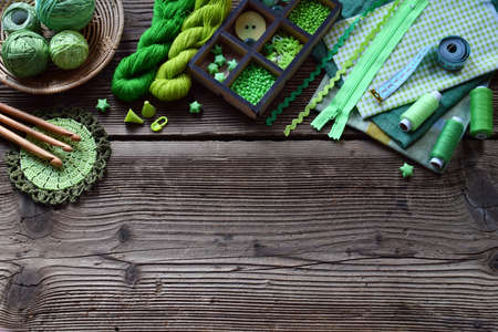 Green accessories for needlework on wooden background. Knitting, crochet, embroidery, sewing. Small business. Income from hobby. DIY Handmadeの写真素材