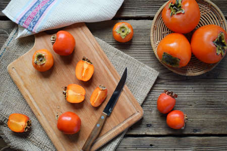 Different varieties of persimmons on wooden background. Delicious ripe orange persimmon. Organic fruits. Copy space. Selective focus.の写真素材