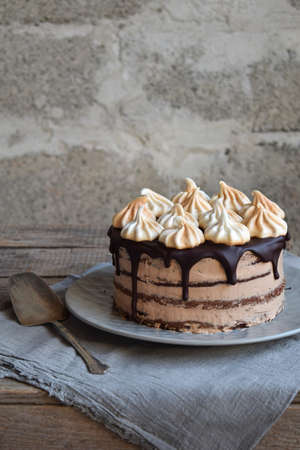 Chocolate cake decorated with rosettes of meringue cream: chocolate-nut biscuit, caramel cream. Homemade bakingの写真素材