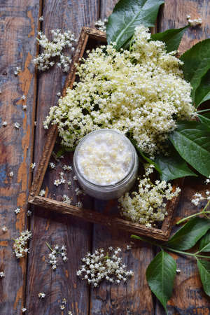 Elderflower sugar and blossom flower in wooden background. Edible elderberry flowers add flavour and aroma to drink and dessert Copy spaceの写真素材