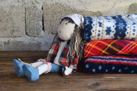 The Stack of warm woolen blankets and doll on wooden background. Childrens textile toys. Home...