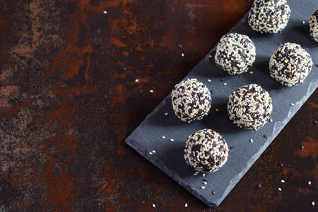 The healthy raw energy bites with flax seeds, almonds, banana and dates. Vegan truffles in sesame...