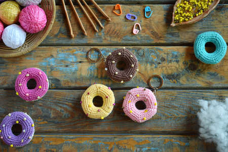 Making crochet amigurumi donuts. The toy for babies or trinket. On the table threads, needles, hook, cotton yarn. Handmade gift. Income from hobby. DIY crafts concept.の写真素材