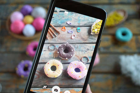 Making crochet amigurumi donuts. The toy for babies or trinket. On the table threads, needles, hook, cotton yarn. Handmade gift. Income from hobby. DIY crafts concept.の写真素材