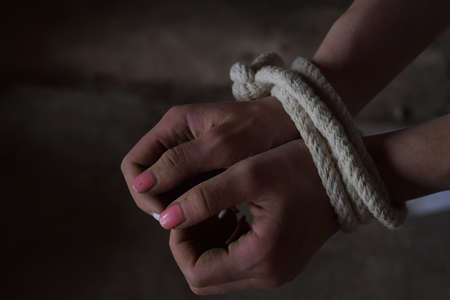 Female hands tied with rope, terrified, hostage, afraid. Stop violence against woman, sexual abuse,...