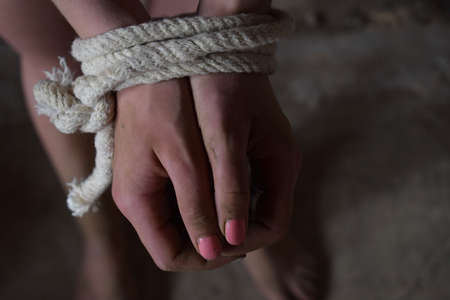 Female hands tied with rope, terrified, hostage, afraid. Stop violence against woman, sexual abuse,...