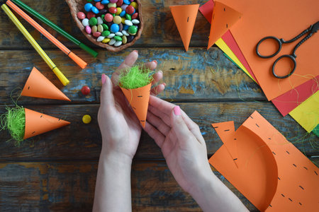 Carrots gift Bag for candies. DIY paper craft with your own hands together with children. Easter treat box. Art project for kids. Step by step guide.の写真素材