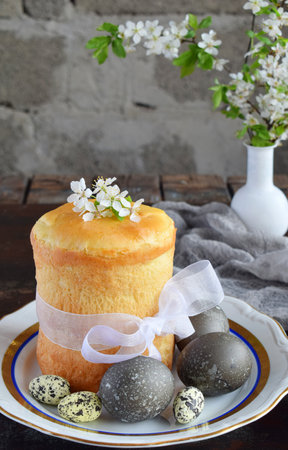 Happy Easter concept. Sweet bread with dried fruits and colored eggs. Holidays breakfast. Orthodox kulich. Festive table place setting decoration with paska, blossom twigs.の写真素材