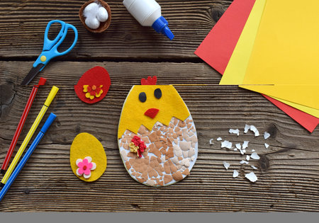 Making of handmade Easter decoration. Child made greeting card from eggshell. Childrens DIY concept, gift with your own hands. Hobby, paper crafts at home or in kindergarten.の写真素材