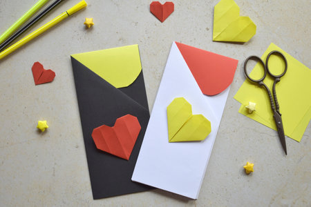 Handmade Crafting Process of a DIY Greeting Card with Origami Paper Hearts, Glue Application, Creative Stationery, Scissors, and Colorful Decorative Elements on a Light Artistic Backgroundの写真素材