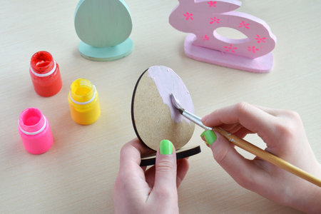 Making Easter decoration - easter eggs and bunny. Painting and coloring wooden toys of brushes and gouache. Creative process. Children's DIY concept.の写真素材