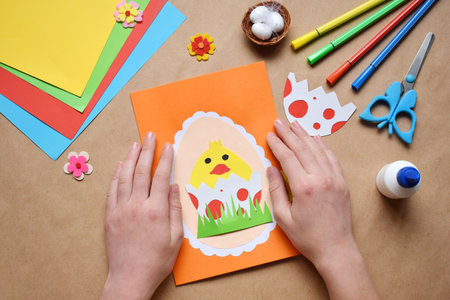 Making of handmade Easter decoration. Child made greeting card in egg shape. Childrens DIY concept, gift with your own hands. Hobby, paper crafts at home or in kindergarten.の写真素材