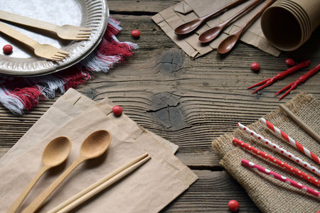 Natural Brown Eco Tableware Set on Vintage Wooden Background. Recyclable and Compostable Forks, Spoons, Paper Straws, and Cups for Environmentally Friendly Dining and Takeaway Useの写真素材