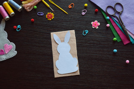 DIY handmade felt bunny ornament, Easter decoration project flat lay, colorful craft supplies, scissors, threads, beads, buttons, creative festive background, top view, spring crafting materialsの写真素材