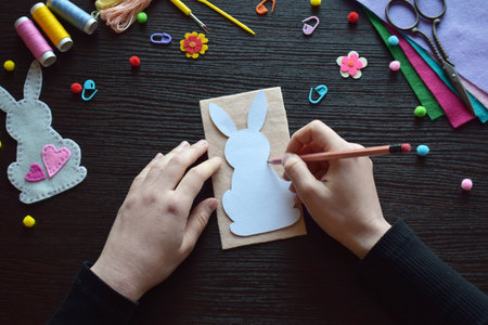 Drawing pattern bunny felt ornament, Easter crafting workspace, DIY project, scissors, threads, colorful buttons, creative process, handmade festive decoration, spring holiday preparationの写真素材