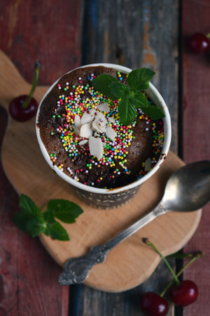 Chocolate dessert topped with whipped cream colorful sprinkles and mint served in a coffee cup on rustic wooden boards perfect for sweet cafe menus bakery advertisements and cozy food presentationsの写真素材