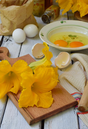 Fresh eggs and bright yellow Zucchini flowers arranged on a rustic wooden cutting board perfect for organic farm food concepts culinary backgrounds and seasonal autumn harvest themesの写真素材