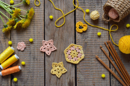 Top view of handmade crochet flowers yarn balls wooden sticks and spring dandelions arranged on rustic table perfect for DIY craft designs handmade decor and seasonal artisan backgroundsの写真素材