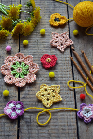 Decorative spring flat lay with handmade crochet floral motifs yellow yarn and dandelions perfect for seasonal craft promotions DIY backgrounds and artistic compositionsの写真素材