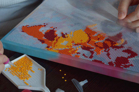Hands working on diamond painting placing colorful beads on a canvas creating an artistic vibrant mosaic perfect for DIY crafting hobbies and creative handmade art conceptsの写真素材